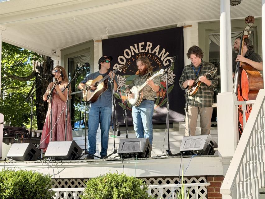 Five piece bluegrass band performs from the porch of a home