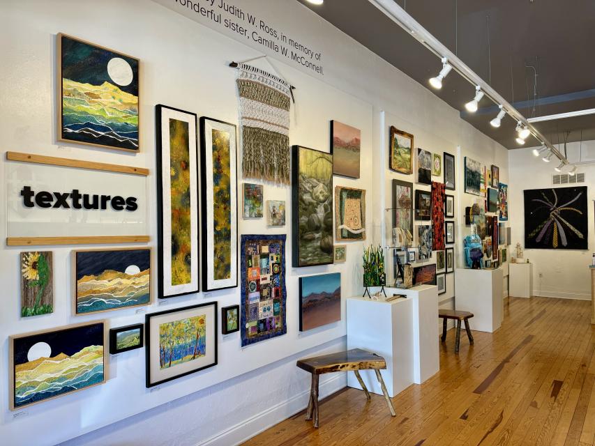 Framed art hangs on a cream colored wall with track lighting