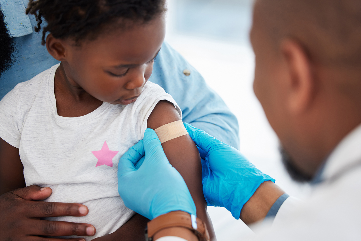 Healthcare worker placing bandage on child's arm after a vaccination.