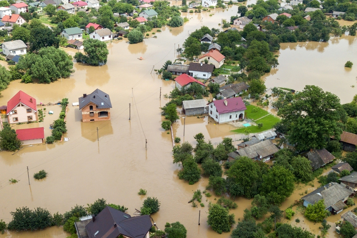 Aerial view of a flooded community with homes, trees, and water covered streets.