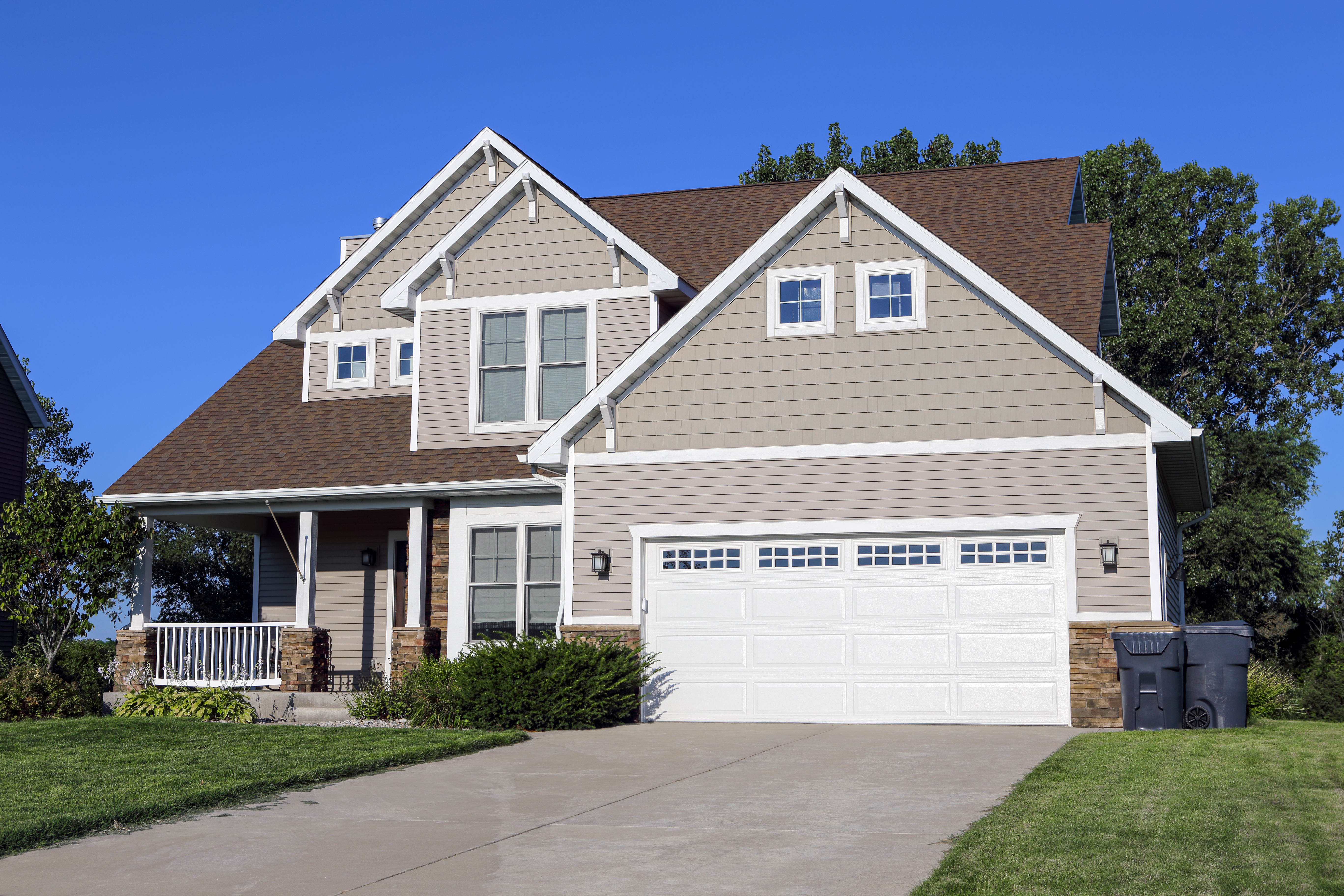 Two story, tan sided suburban home.