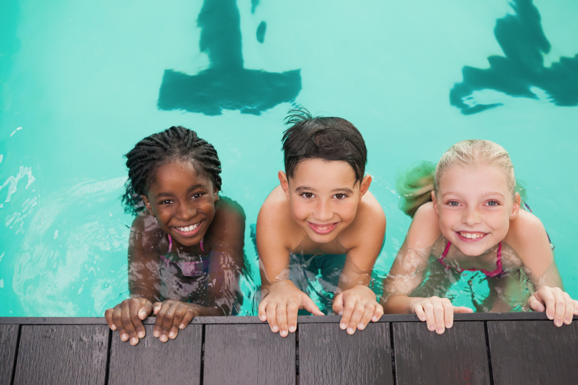 Three children in a pool smiling