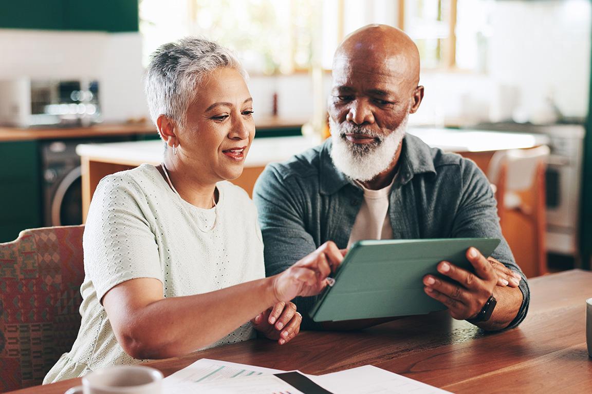 A senior couple looking at a tablet reviewing their taxes.