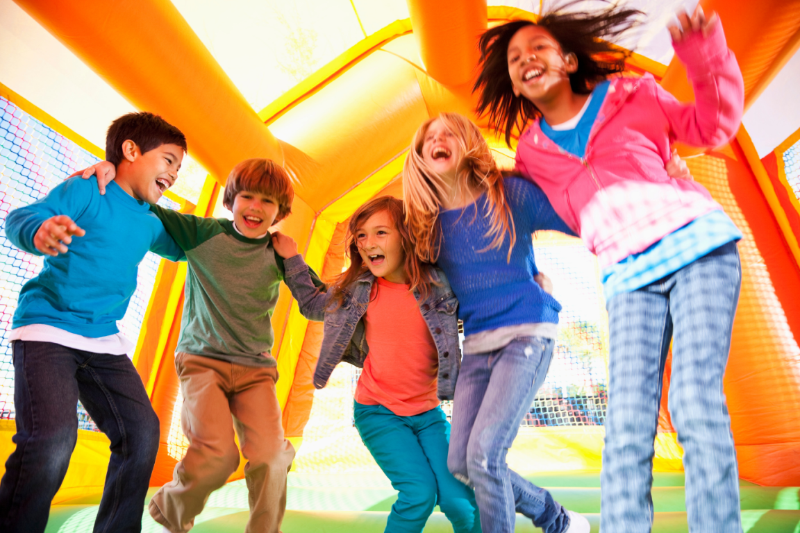 A group of kids energetically bouncing on a large inflatable bouncer, enjoying a fun-filled day outdoors.