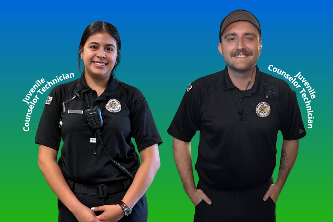 Two juvenile counselor technicians, a woman on the left and a man on the right, both smiling and wearing black uniforms against a blue-to-green gradient background.