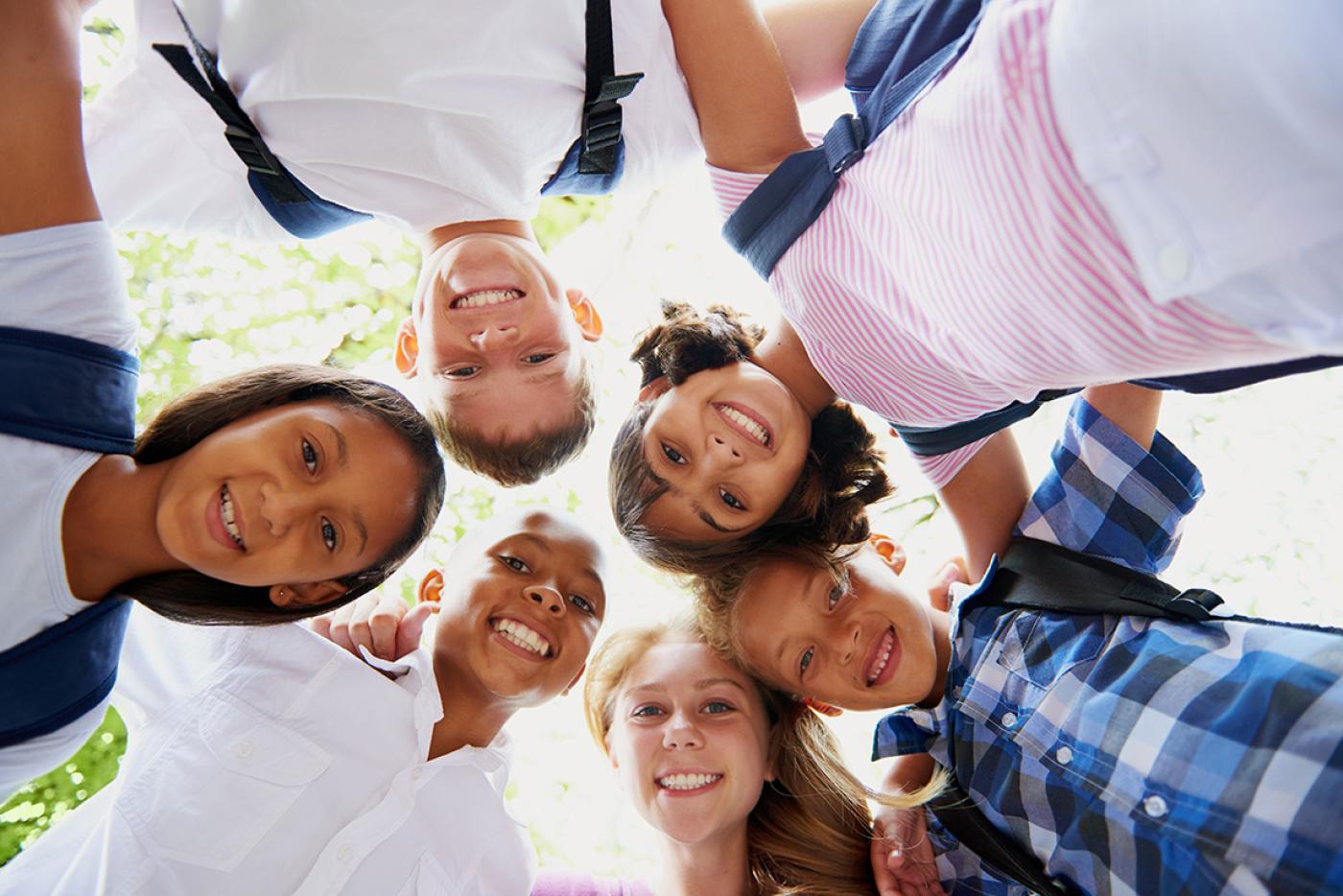 Elementary school kid friends smiling in a circle.