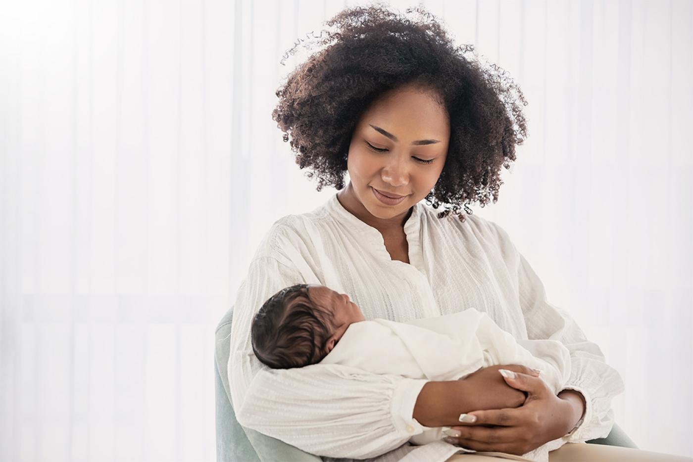 Smiling mother cradling her infant child in her arms.