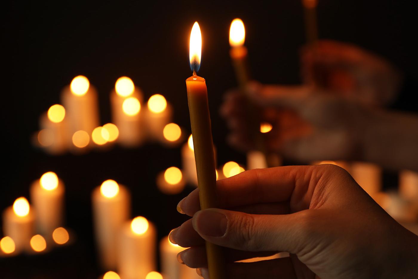 Hand holding candle at candlelight vigil.