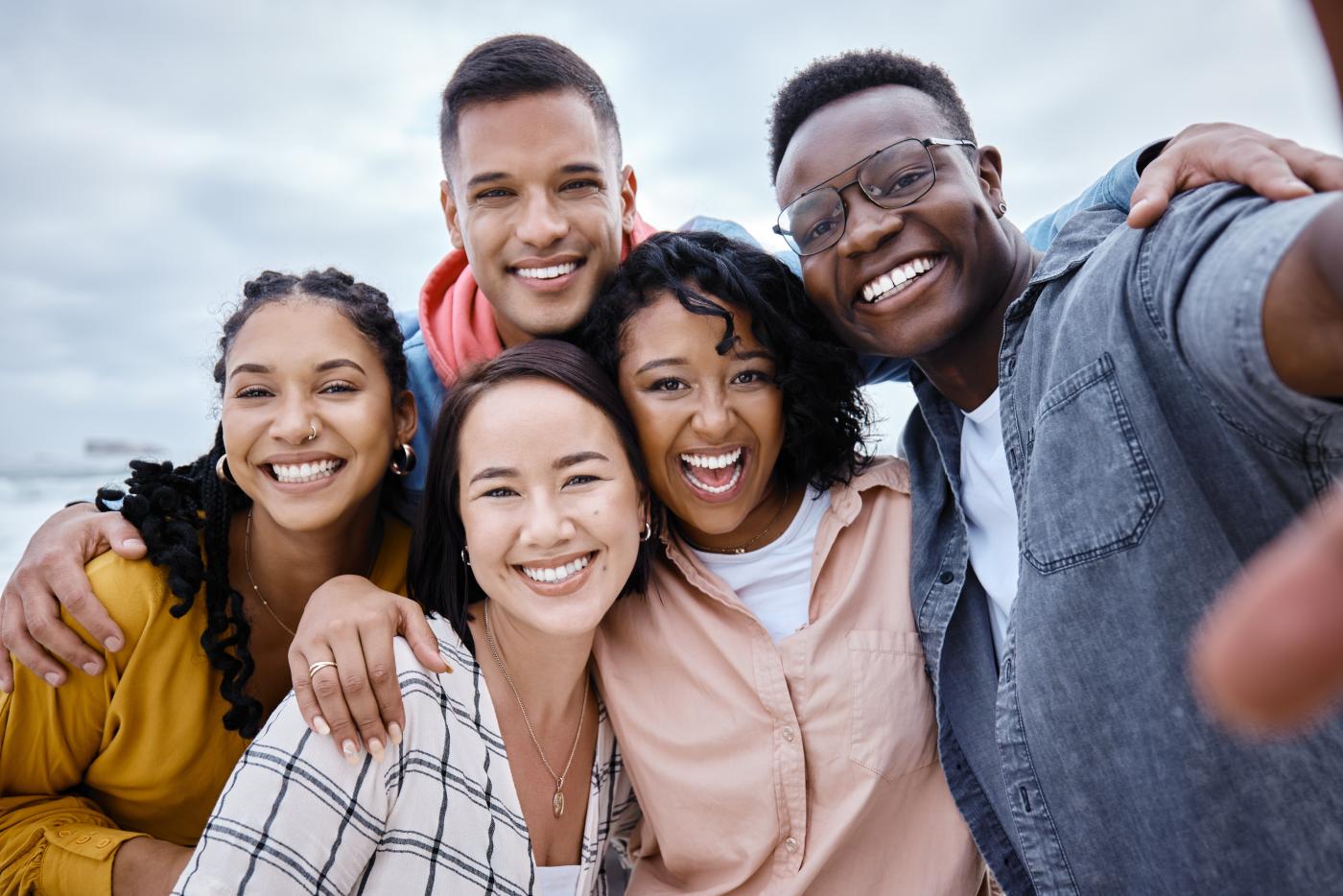 A smiling, diverse group of multiracial friends taking a selfie together.