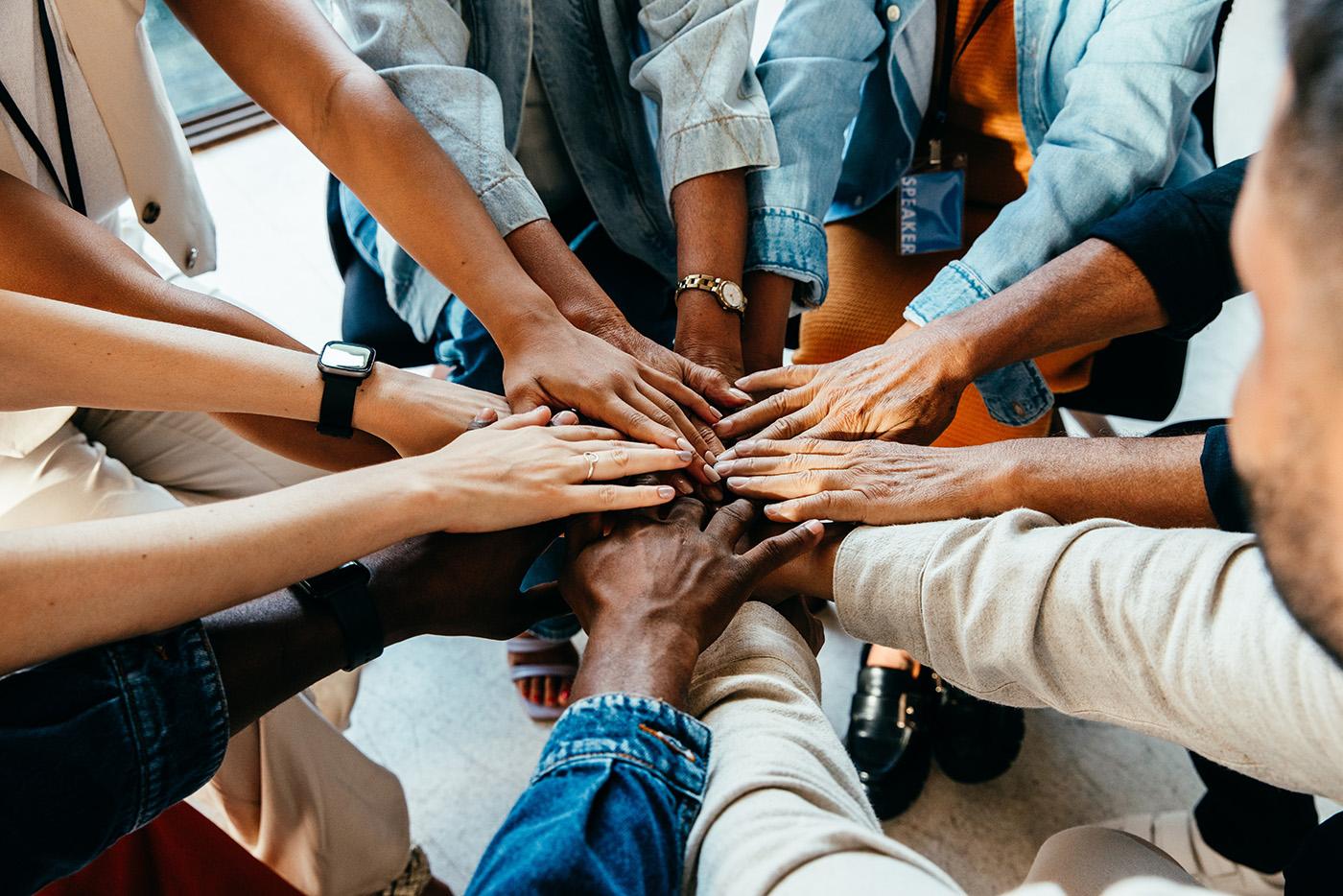 A circle of people with hands in center overlapping in unity and teamwork.