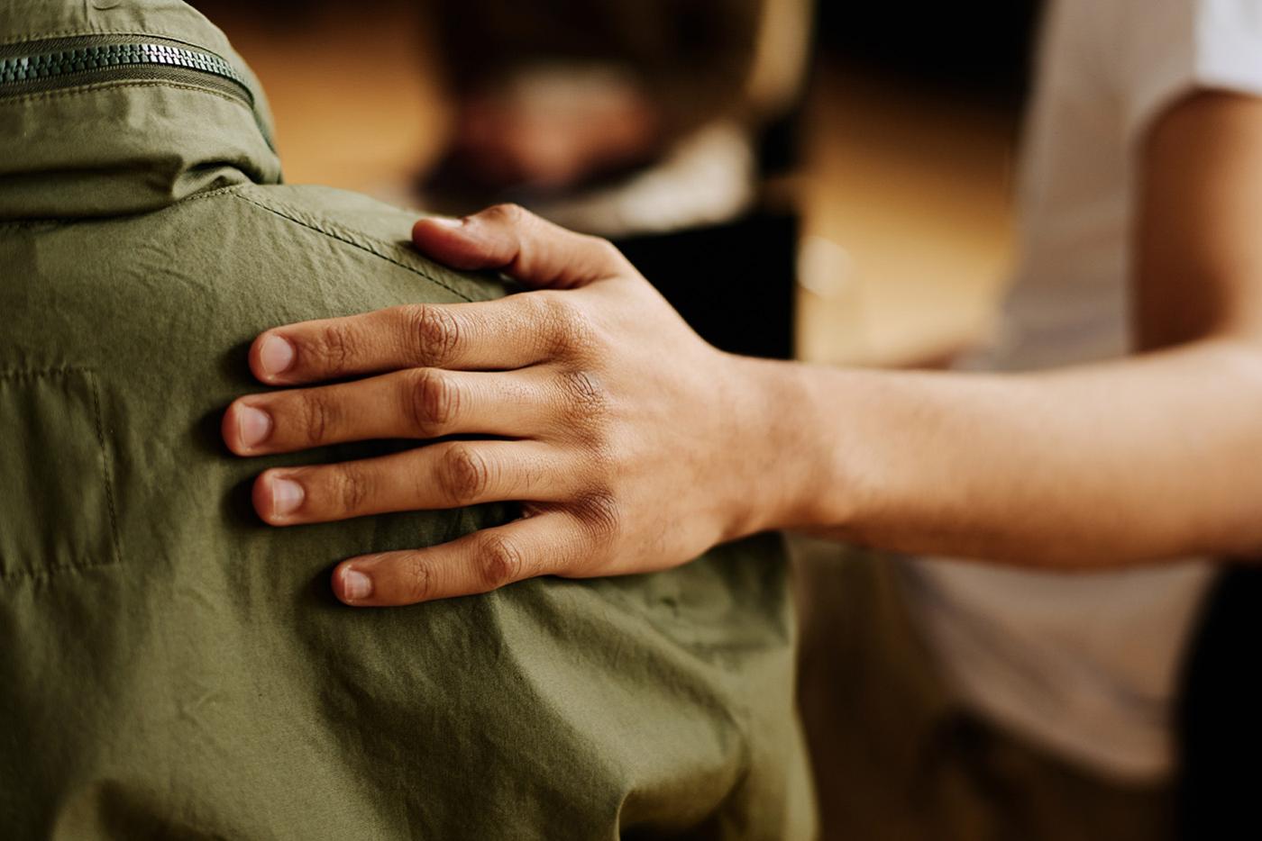 Hand of young supportive man consoling and supporting someone at a group meeting.