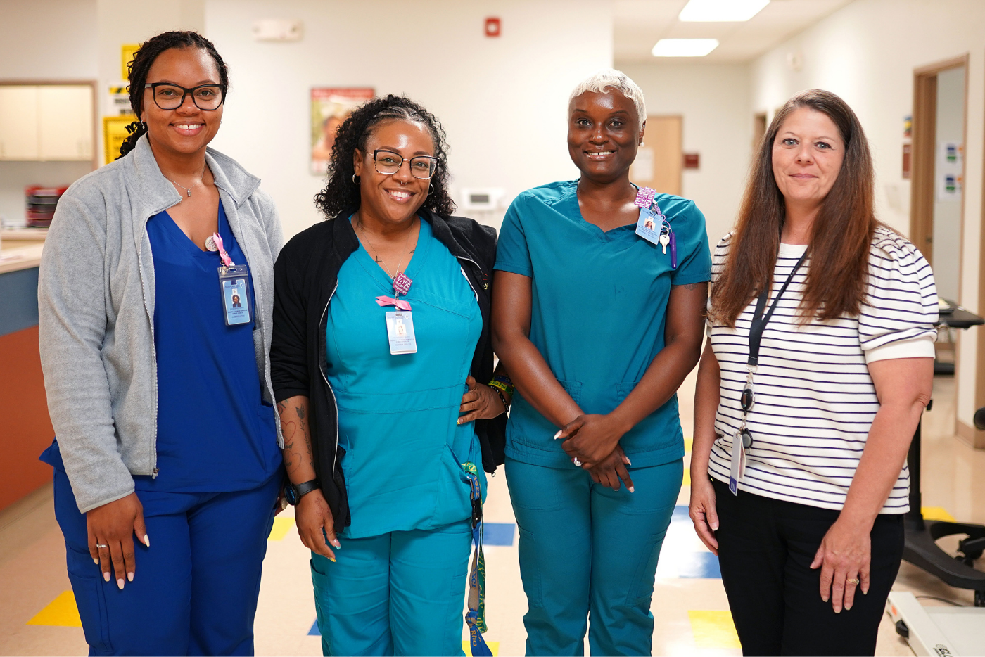 Group of four smiling members of the Guilford County Public Health nursing staff in a county facility.