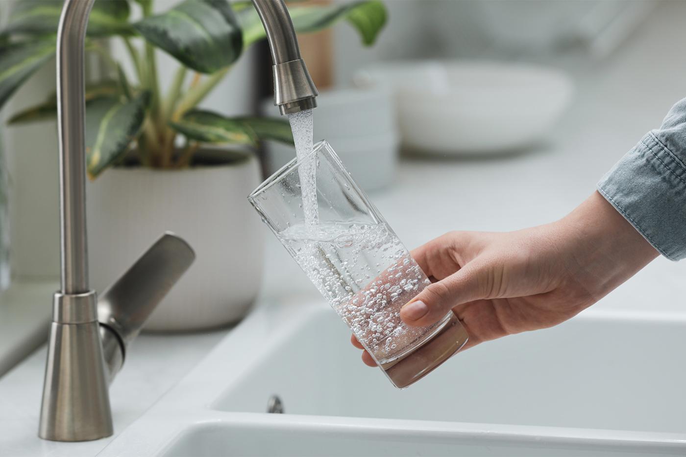 Close up of Woman filling glass with water from tap in kitchen.