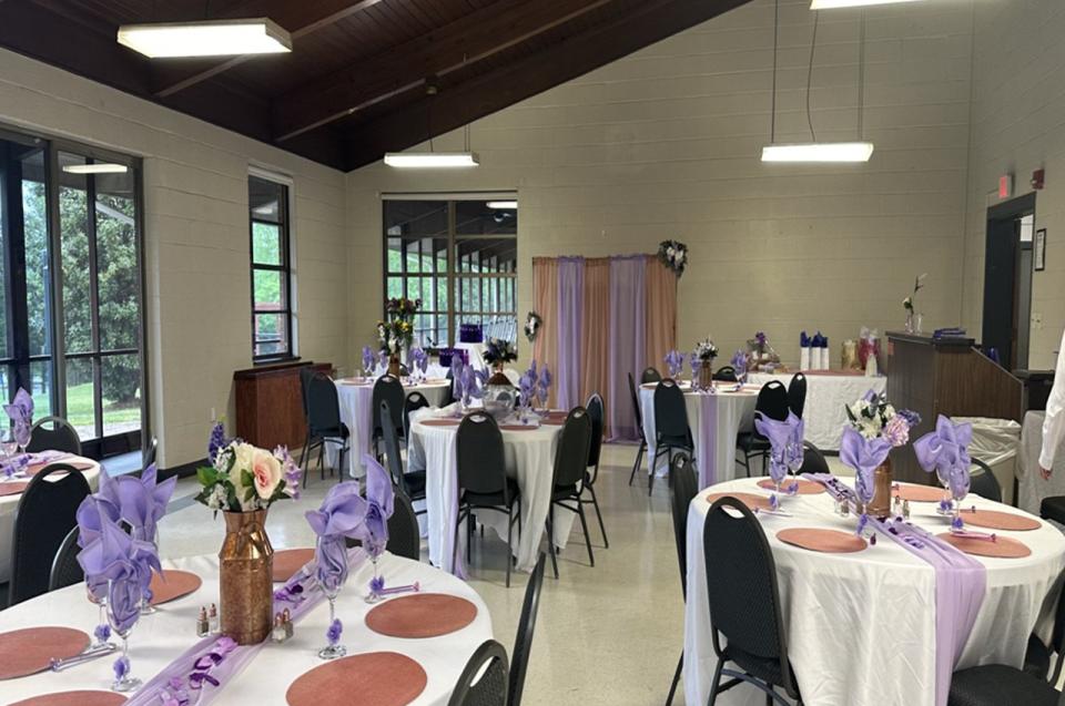 The Cedar Room at Bur-Mil Park Event Center featuring tables with tablecloths and place settings and chairs for an event.