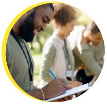 A young man with a pen recording information on a clipboard.