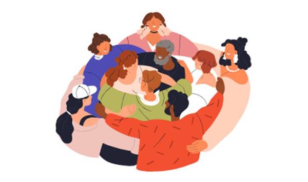 A group of people in a circle hugging one another in support.