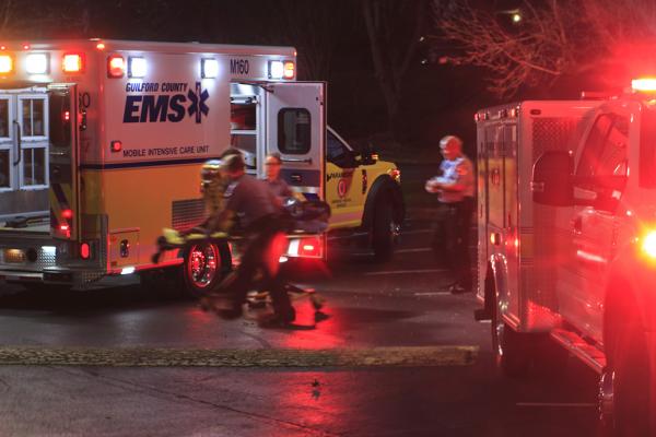 Emergency medical technicians providing care for someone on a gurney to be transported on their ambulance.