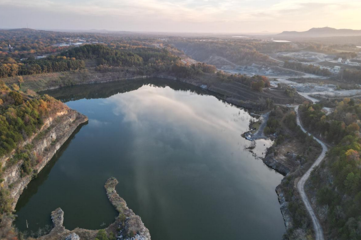 Drone footage overlooking a filled quarry lake or pond