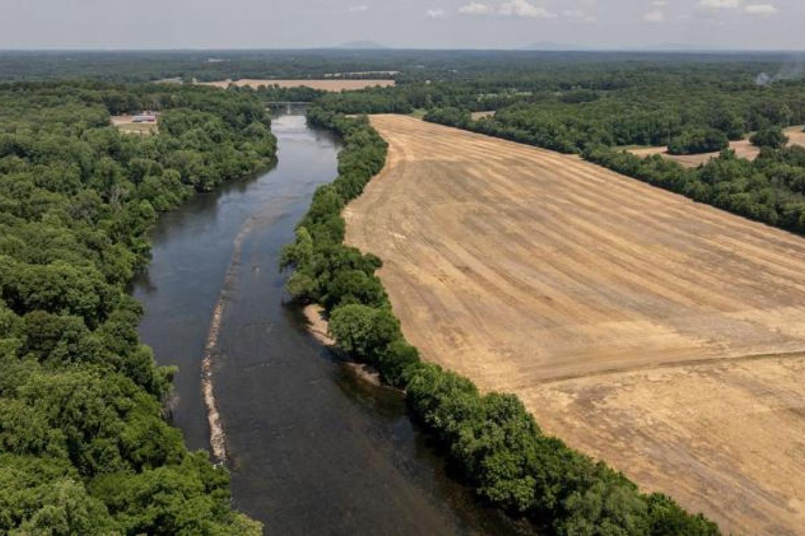 Aerial image of Shallow Ford State Historic Site with the Yadkin River bordering a large field of open farm land.
