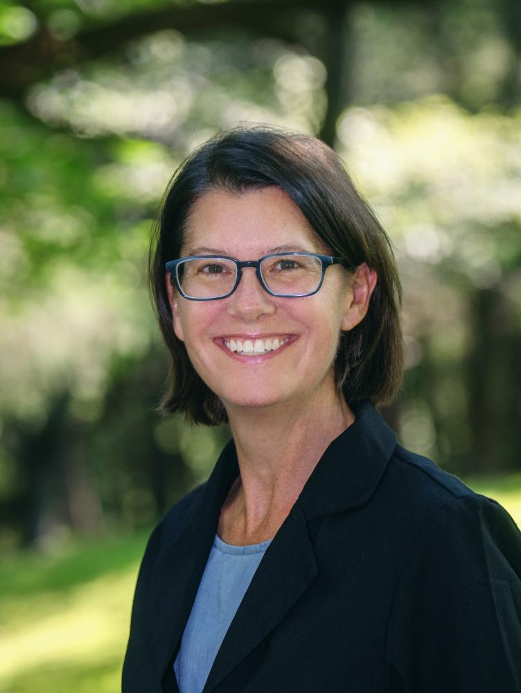 A woman in a black blazer smiles at the viewer