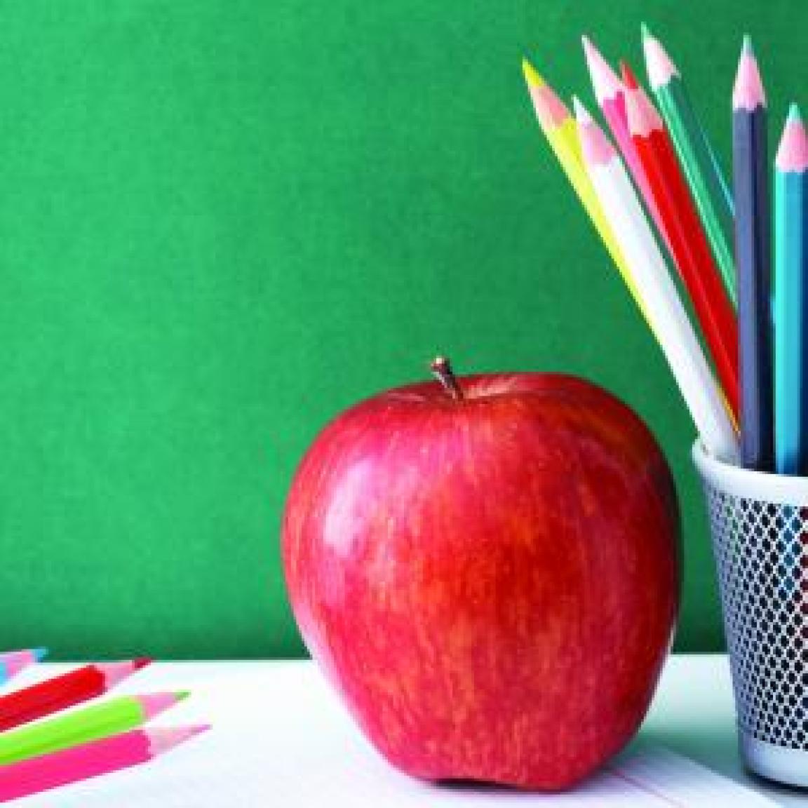 An apple and colored pencils on a desk