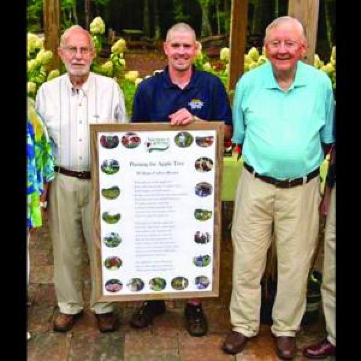 Three men standing with a large framed poster
