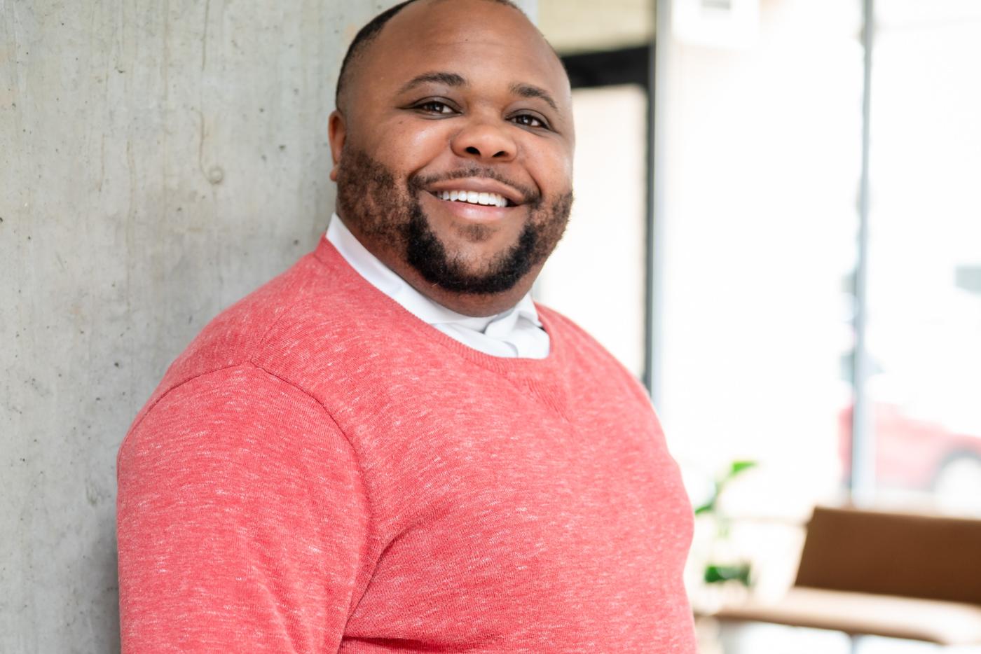 Dr. Gatson smiling and leaning against a wall