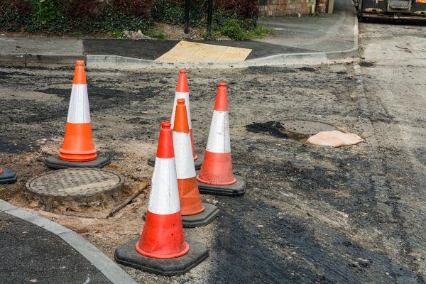 orange and white construction cone around pothole
