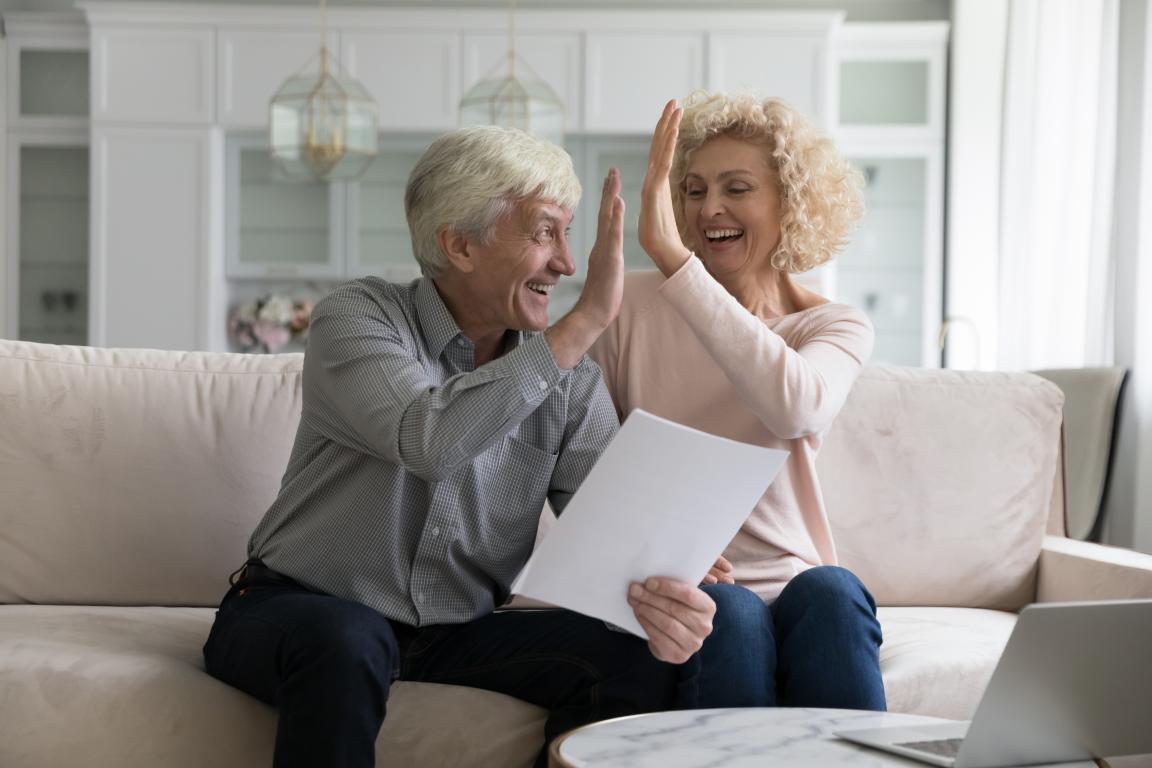 Old couple high-fiving each other with paper in hand
