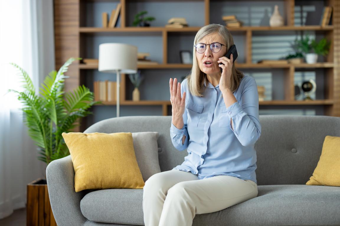Elder woman on phone with exasperated expression, hand in air.