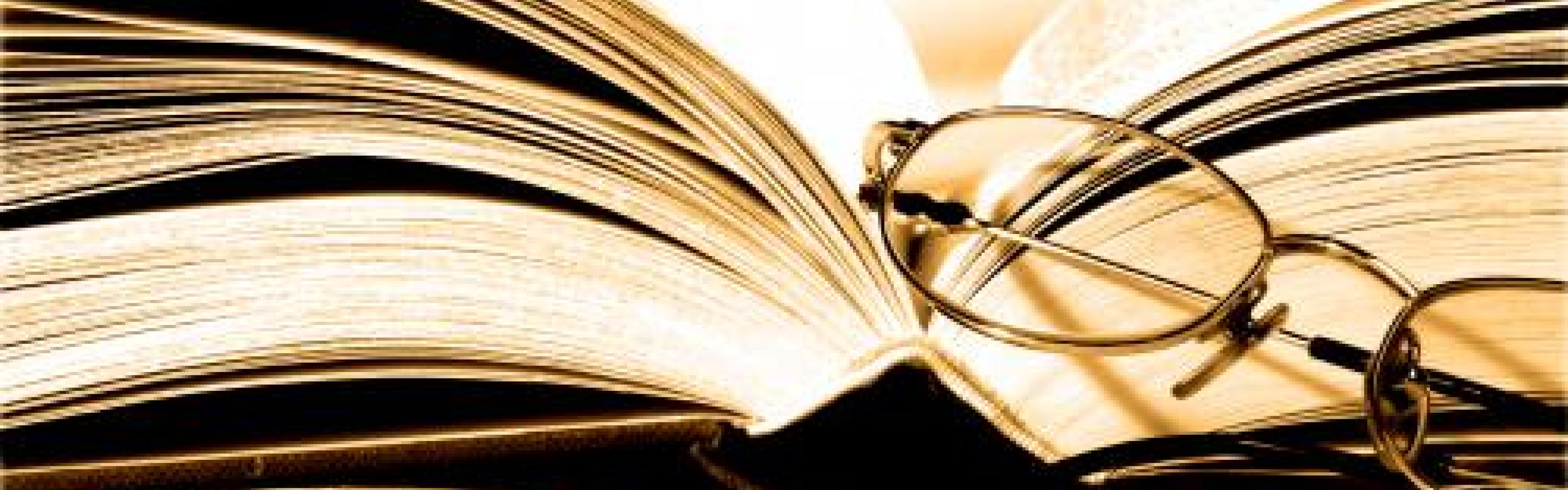 An open book with glasses leaning on it