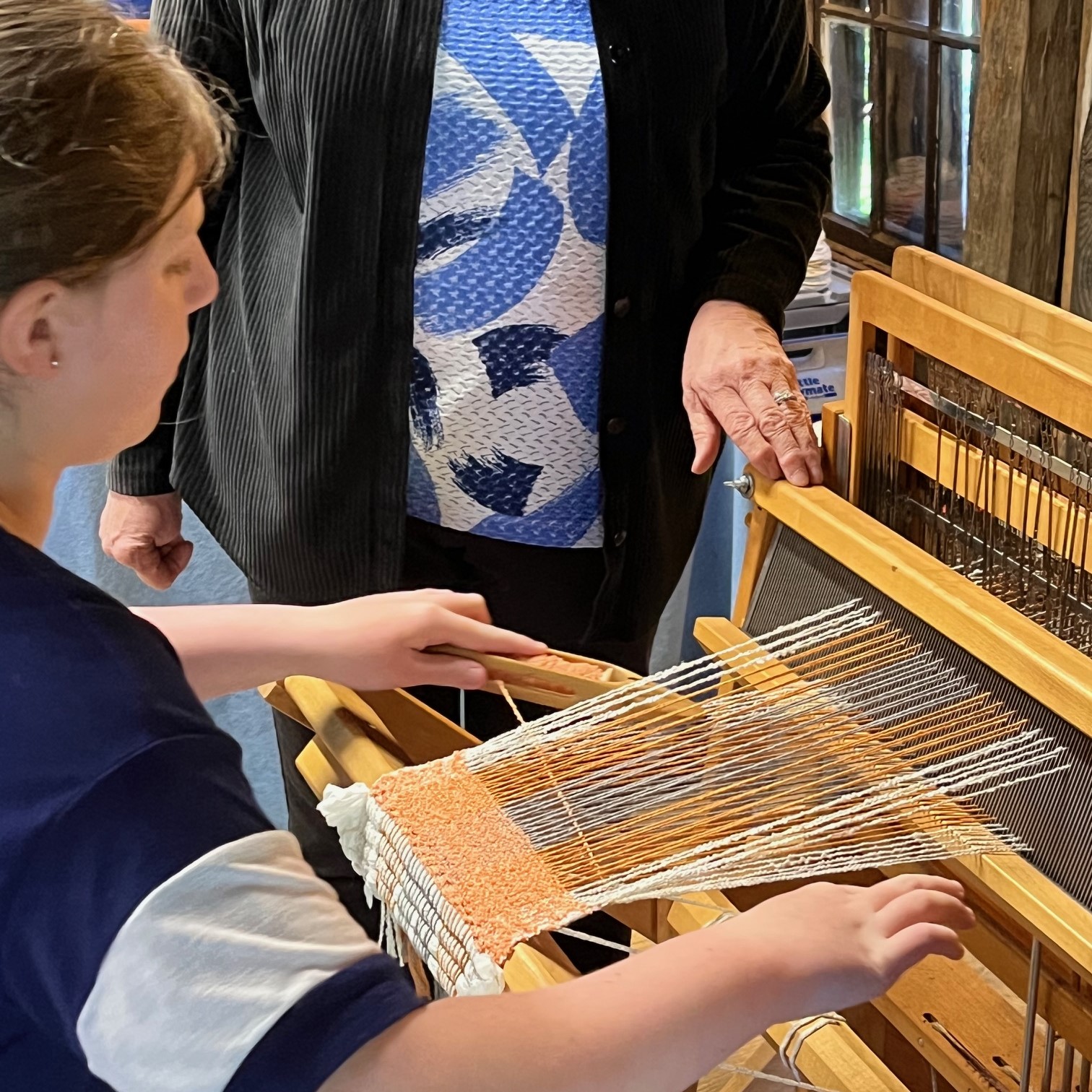 women learning how to weave on barn loom