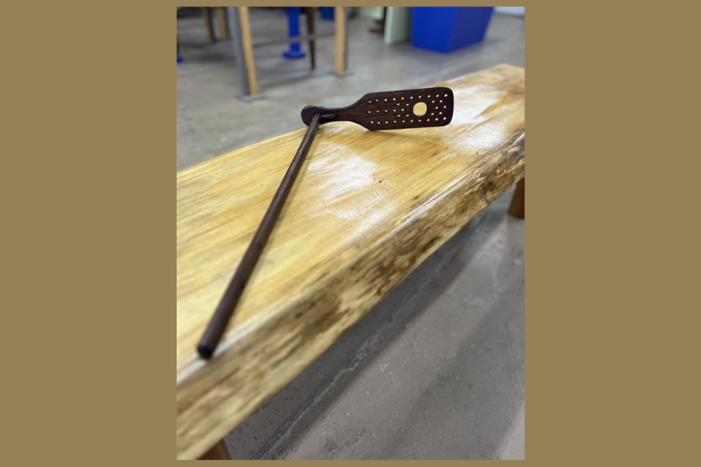 wooden pole with a paddle with several holes on one end