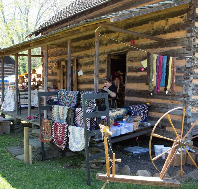 Museum cabin with rugs, yarn, and spinning wheel on display