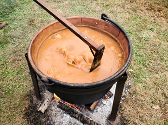 apple butter in a large kettle pot with a paddle stirring