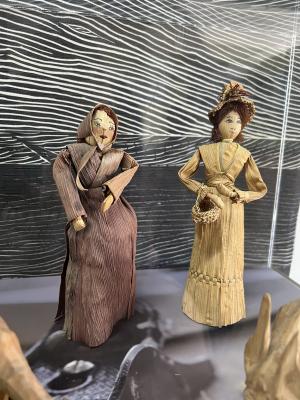 Two cornshuck dolls with painted faces in a display case