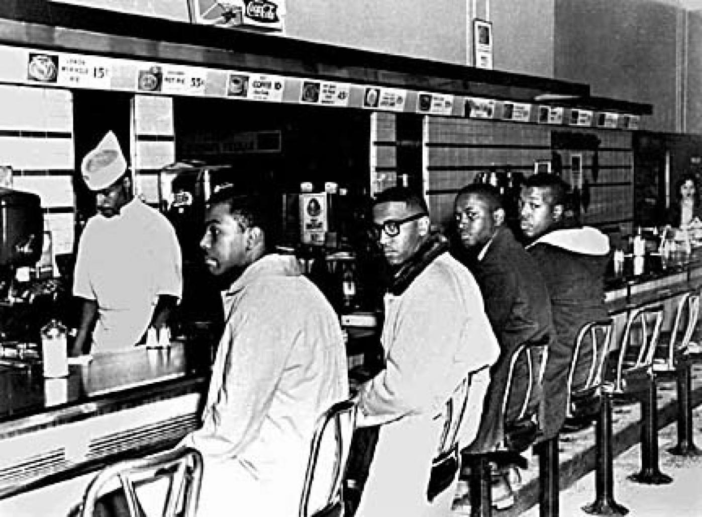 The Greensboro Sit-Ins showing young black men seated at a counter. Photo from the Greensboro News & Record