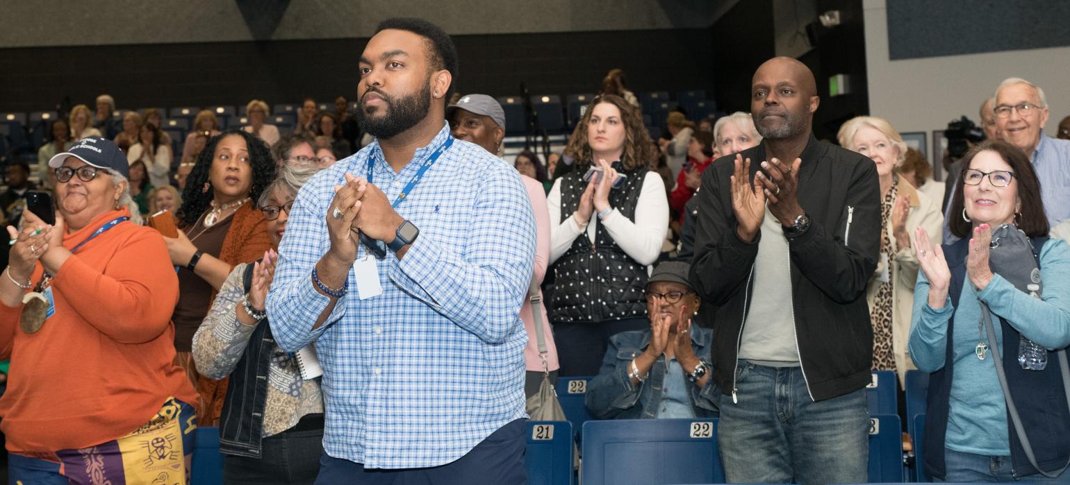 Conference attendees share applause after a presentation.