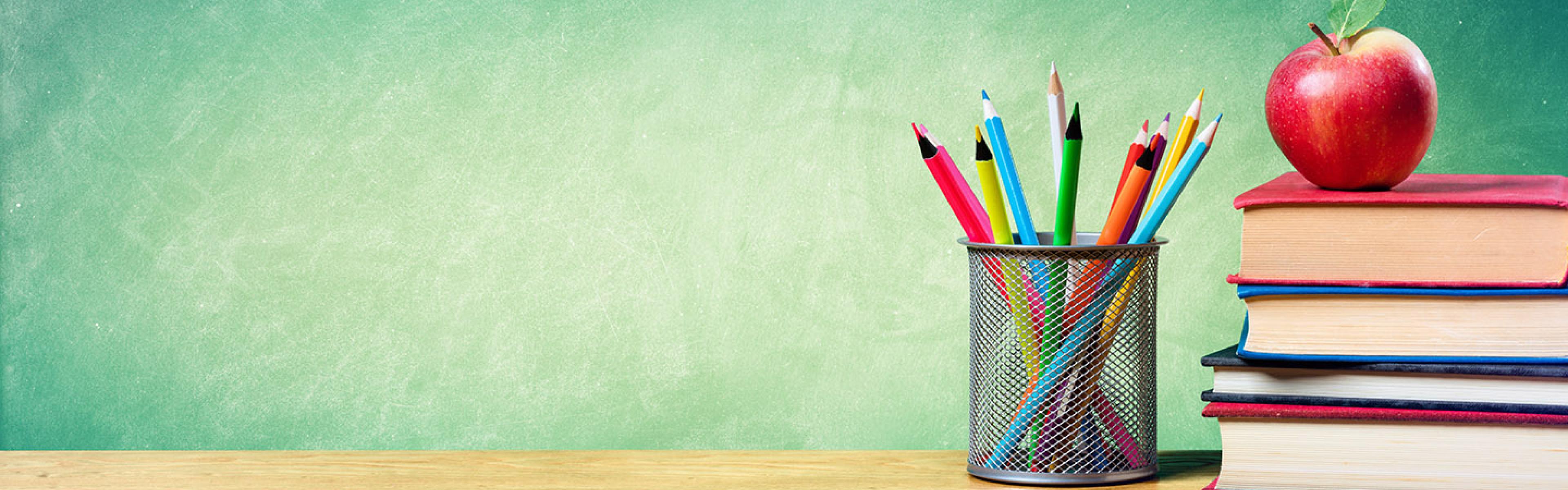 Books, an apple, and a pencil holder with pencils.