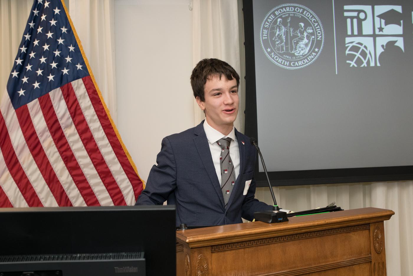 Ian House speaks at a podium.