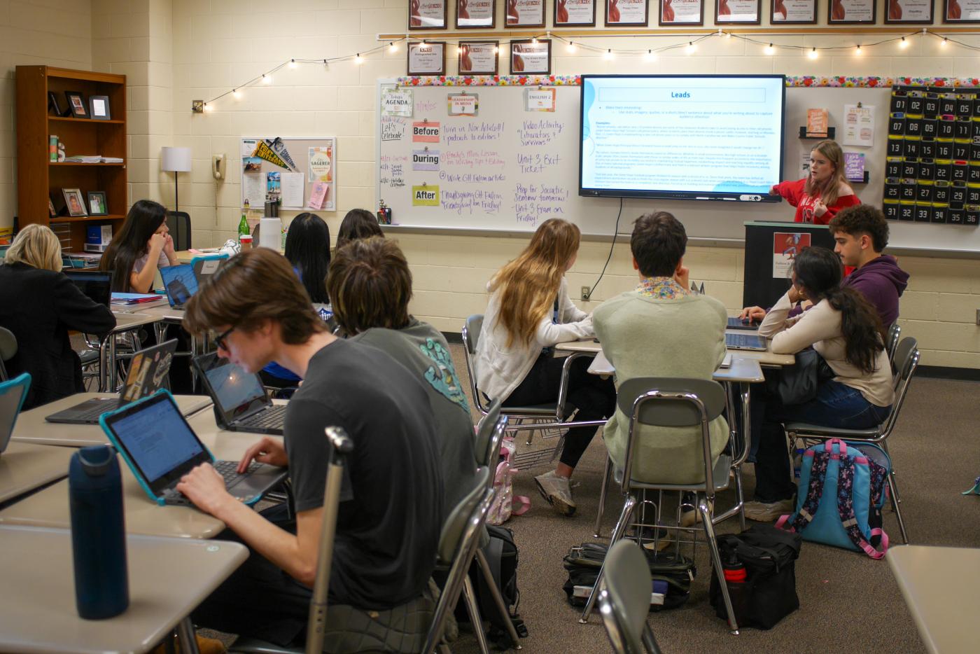  Members of The Green Hope Falcon’s staff gather for an editorial meeting. One student is pointing at the smart board while speaking.