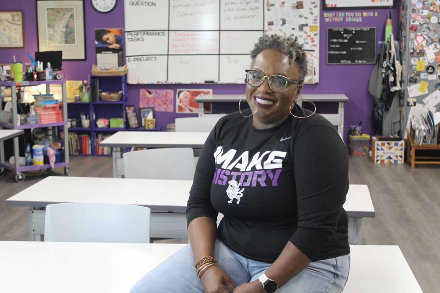 Valencia Abbott Gilder Lehrman sitting on a desk in a classroom.