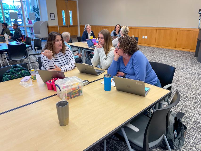 Three educators sitting around a table engaged in discussion.
