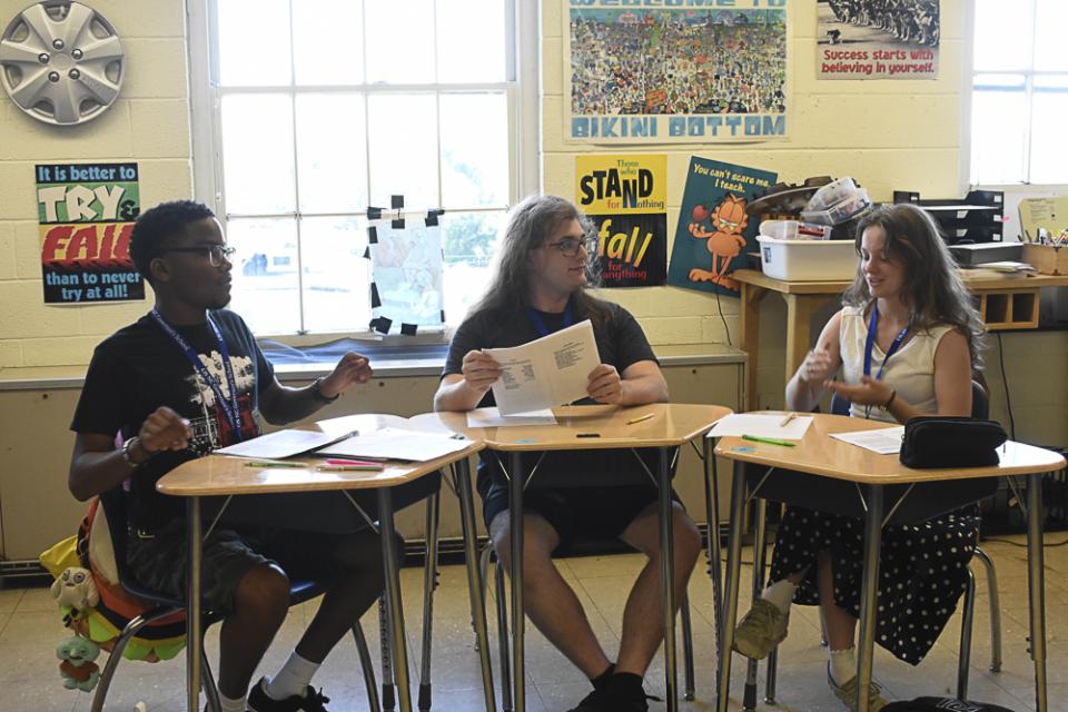 GS students in a classroom converse in a small group.