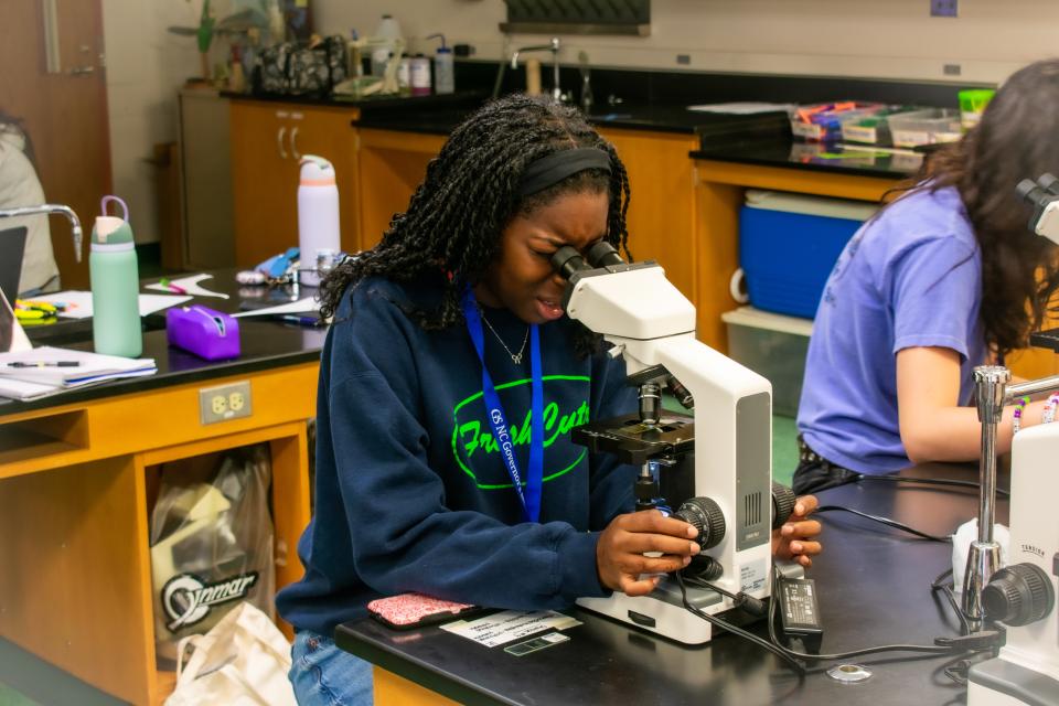 A GS student looks through a microscope in a Natural Science class.
