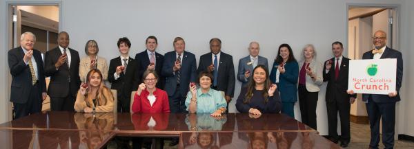 State Board of Education members pose with apples and a sign that reads “NC Crunch.”