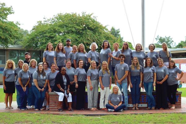 Principal Christy Propst, seated, poses with her staff outside Morehead City Elementary School.