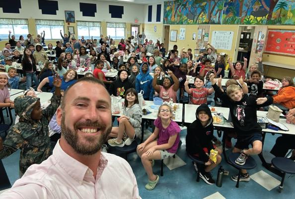 Principal John Lassiter of Hertford Grammar School takes a selfie with students in the school cafeteria.
