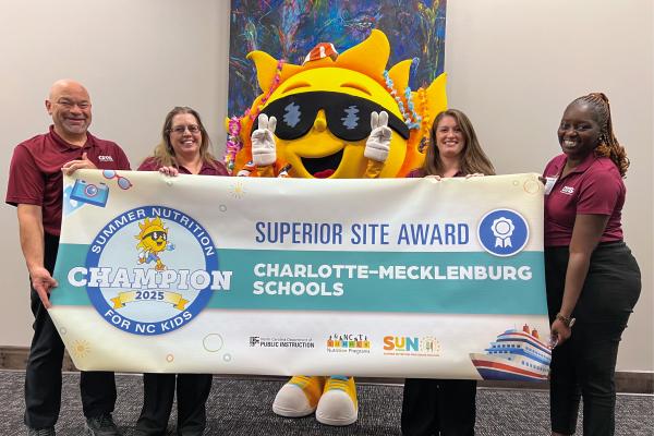Members of the Charlotte-Mecklenburg Schools nutrition staff hold a banner that recognizes their district for receiving a Superior Site Award.
