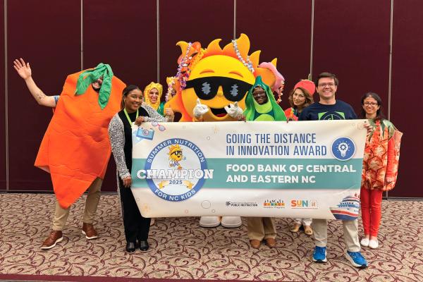 Staff from the Food Bank of Central and Eastern North Carolina hold a banner for receiving the Going the Distance Award.